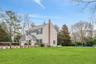 View of front of property with central AC, a chimney, a front lawn, and fence