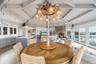 Dining space with light wood-style flooring, rail lighting, a fireplace, beam ceiling, and a notable chandelier