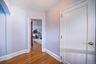 Hardwood flooring with a diagonal pattern, white trim work, and a white interior door with brass hardware
