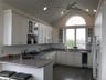 Kitchen featuring glass insert cabinets, a peninsula, vaulted ceiling, white cabinets, and wine cooler