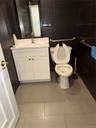 Contemporary bathroom featuring dark horizontal wall tiling, a white vanity with double doors and a countertop sink, a wall-mounted mirror, and a toil