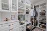The secondary primary closet offers exceptional organization and functionality, featuring custom built-ins with open shelving, drawers, and hanging sp