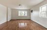 Spacious room featuring wood-finish flooring, white walls, and multiple windows