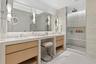 Luxurious primary bath featuring custom vanities, marble floors, walls and shower and lavish freestanding soaking tub.