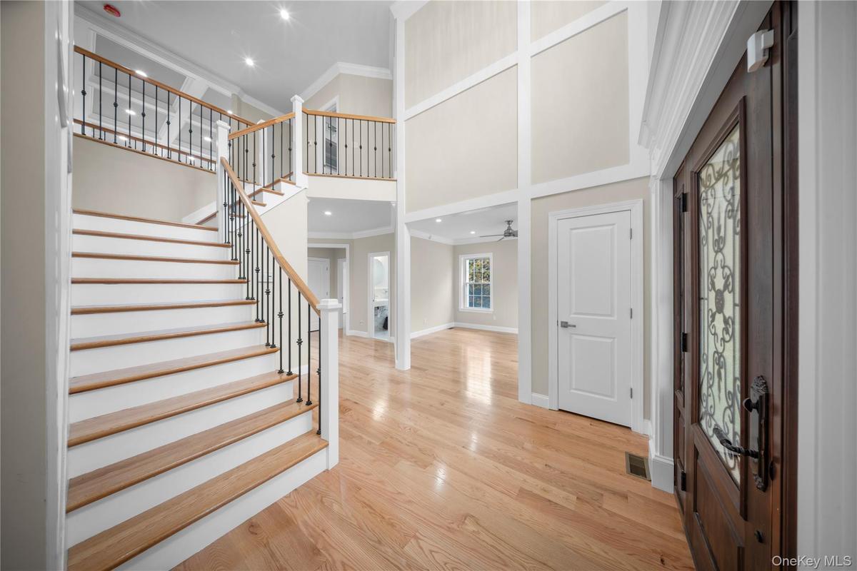 Entrance foyer featuring crown molding, a towering ceiling, a fireplace, light wood-style floors, and recessed lighting