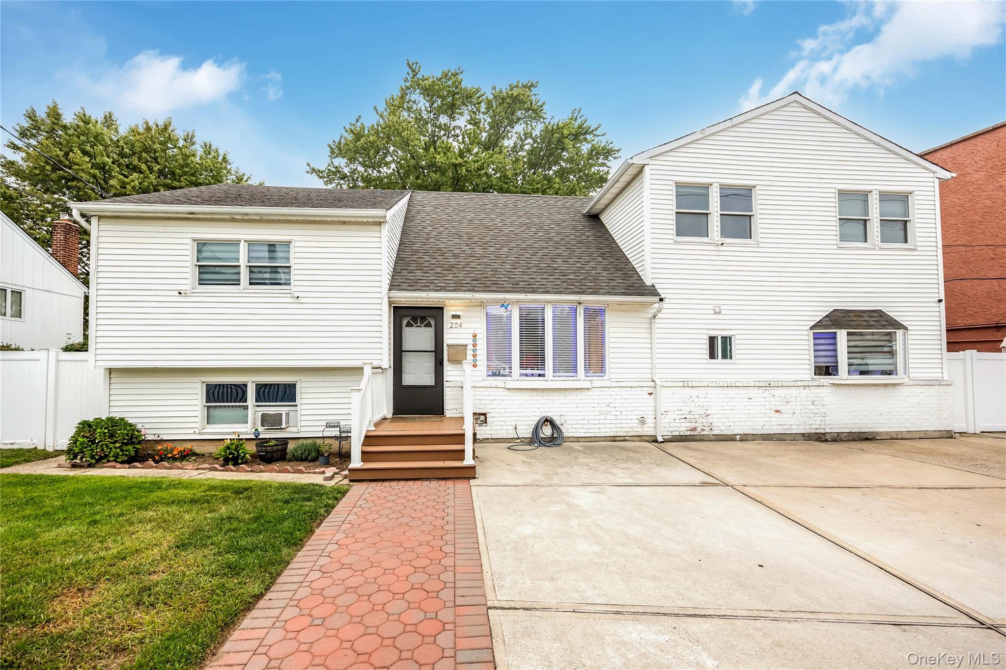 Tri-level home featuring a shingled roof and brick siding