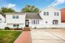 Tri-level home featuring a shingled roof and brick siding