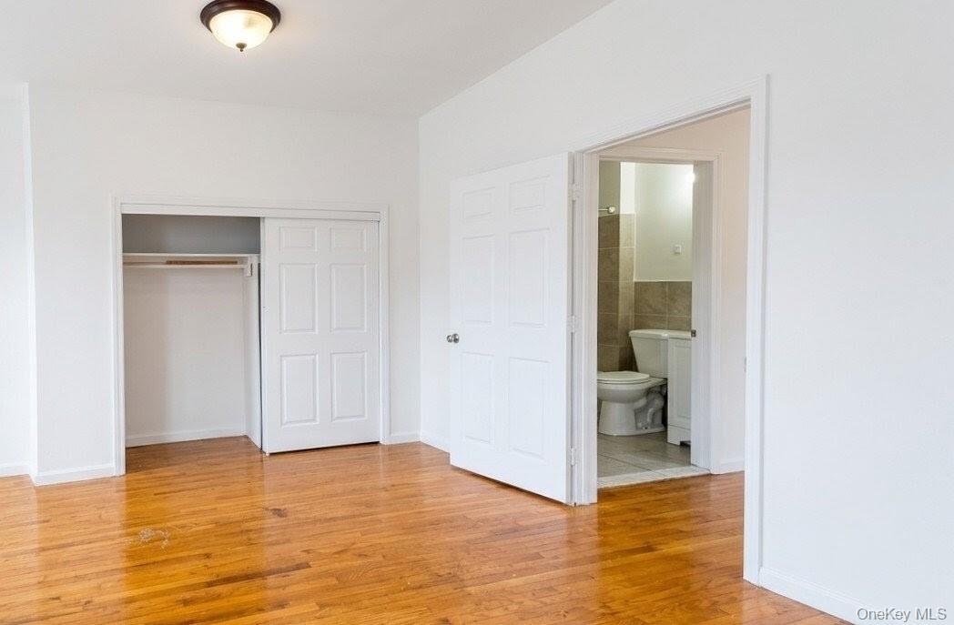 Room featuring wood-finish flooring, a built-in closet with bi-fold doors, and a ceiling-mounted light fixture