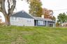 View of front facade featuring a front lawn, a garage, a chimney, and brick siding