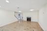 Living area featuring a fireplace with a stone surround and white mantel, recessed lighting, crown molding, and diagonal tile flooring with accent squ