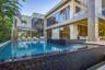 Full rear elevation view with oversized pool, blue mosaic tile spa with spillover, large-format stone deck, teak chaise lounges, stone-clad two-story