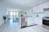 Kitchen featuring a peninsula, white cabinets, under cabinet range hood, light countertops, and stainless steel appliances