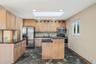 Kitchen featuring stainless steel appliances, backsplash, a skylight, dark stone counters, and a kitchen island