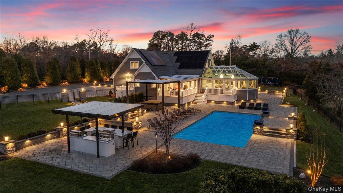 View of pool featuring a patio area, a fenced backyard, an outdoor kitchen, and a sunroom