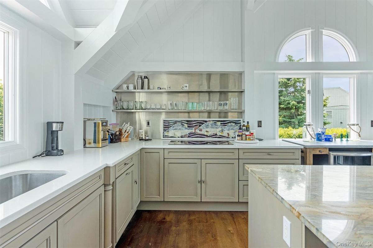 Kitchen featuring plenty of natural light, dark wood finished floors, vaulted ceiling, light stone counters, and white stovetop