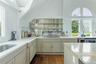 Kitchen featuring plenty of natural light, dark wood finished floors, vaulted ceiling, light stone counters, and white stovetop