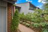 Modern exterior featuring multi-paned windows, a brick accent wall, and a herringbone-patterned paver walkway