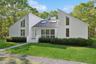 Mid-century modern home featuring a chimney, roof with shingles, and a front lawn