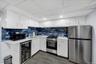 Compact kitchen featuring white cabinetry, a blue tile backsplash, stainless steel appliances