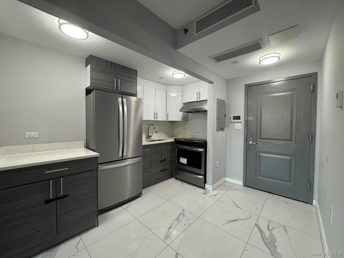 Kitchen with appliances with stainless steel finishes, modern cabinets, white cabinets, and light marble finish floors
