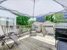 Expansive wood-finish deck with a wood railing and a white tent for shade