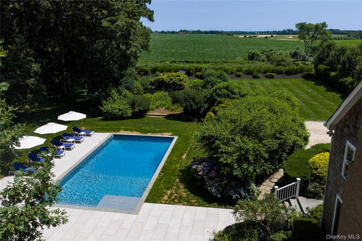 Rectangular swimming pool with a stone paver surround, farm field views