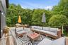 An expansive outdoor deck designed for relaxing and entertaining, featuring multiple seating areas and plenty of room for dining and gatherings. Surro