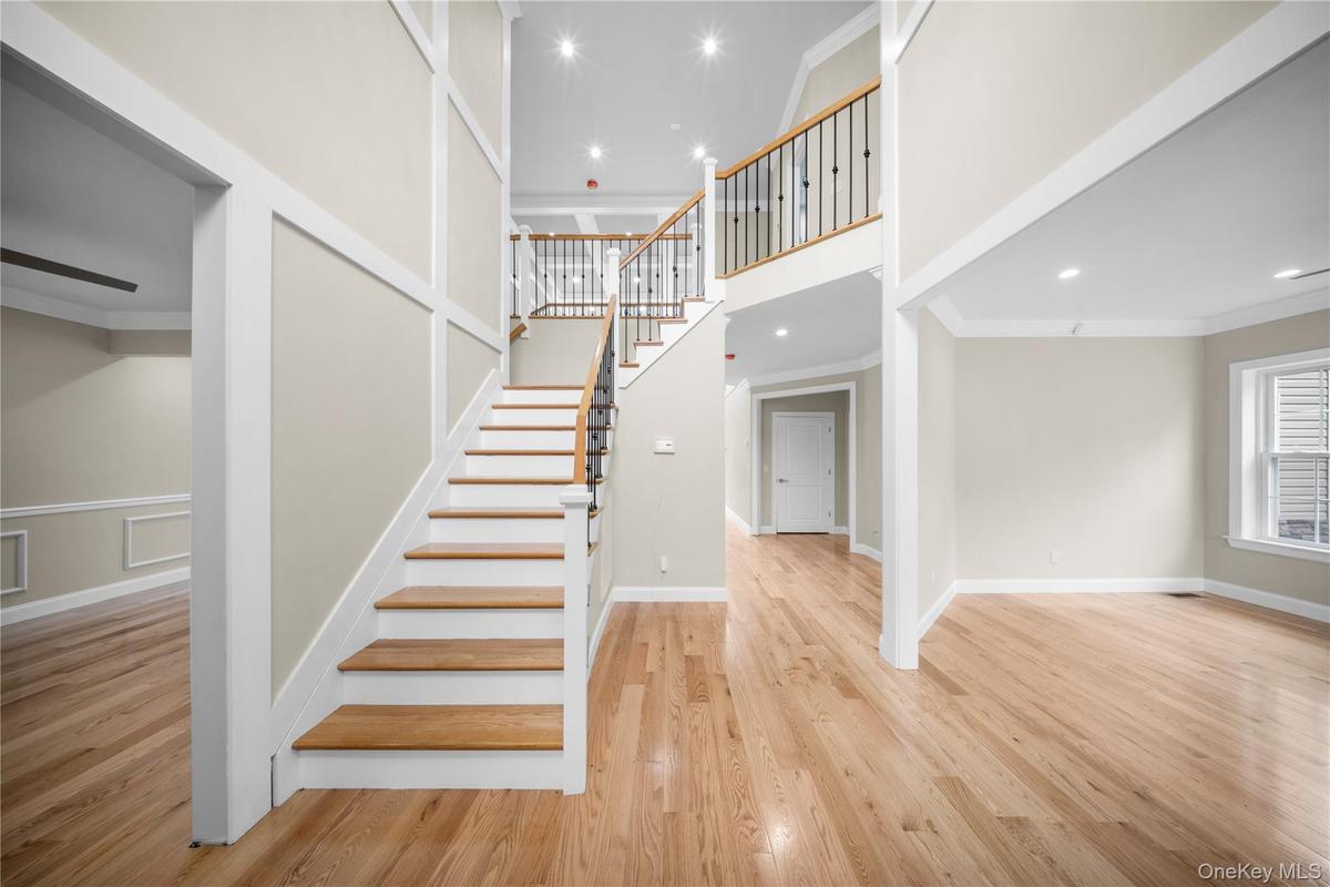 Staircase with ornamental molding, a high ceiling, wood finished floors, and recessed lighting