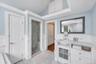 Bathroom featuring a glass-enclosed shower, white vanity with an undermount sink, marble-finish countertop, and decorative mirror