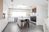 Kitchen featuring light countertops, a skylight, an island with sink, and wine cooler