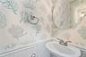 Bathroom featuring a wainscoted wall, a sink, and wallpapered walls