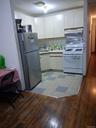 Kitchen with freestanding refrigerator, white range with gas stovetop, light wood finished floors, light countertops, and white cabinets
