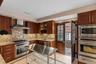 Kitchen featuring light stone countertops, appliances with stainless steel finishes, wall chimney exhaust hood, a warming drawer, and recessed lightin
