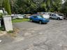 Uncovered parking lot with view of wooded area