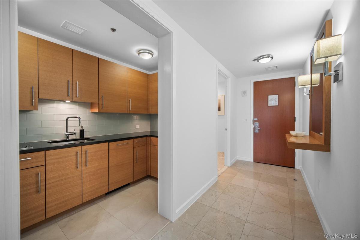 Kitchen featuring a sink, baseboards, brown cabinets, dark countertops, and decorative backsplash