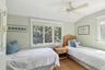 Carpeted bedroom featuring multiple windows, vaulted ceiling, and ceiling fan