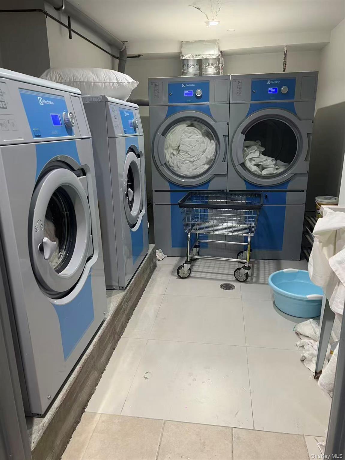 Shared laundry with tile patterned floors and washing machine and dryer