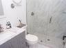 Bathroom featuring a marble finish shower and vanity
