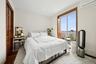 Bedroom featuring an AC wall unit, light wood-style flooring, a closet, a baseboard radiator, and recessed lighting