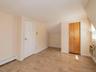 Additional living space featuring light wood finished floors, a baseboard radiator, vaulted ceiling, and an AC wall unit