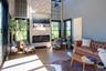 Living room with a glass covered fireplace, wood finished floors, and a high ceiling