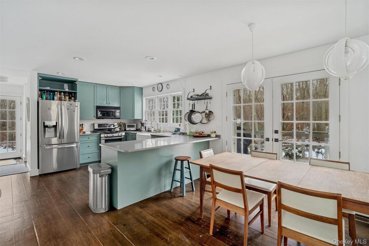 Kitchen featuring open shelves, stainless steel appliances, green cabinets, french doors, and a peninsula