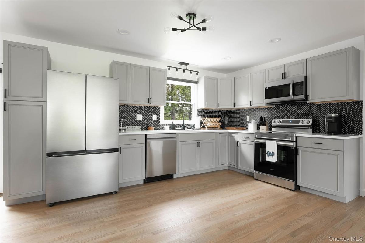 Kitchen featuring gray cabinets, appliances with stainless steel finishes, backsplash, light wood finished floors, and recessed lighting