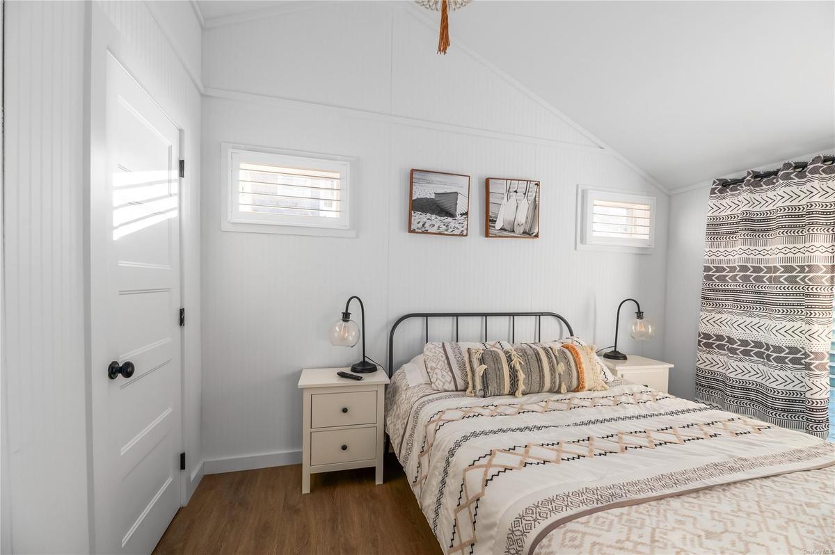Bedroom with lofted ceiling and dark wood-type flooring