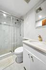 Full bath featuring vanity, a marble finish shower, and tile walls