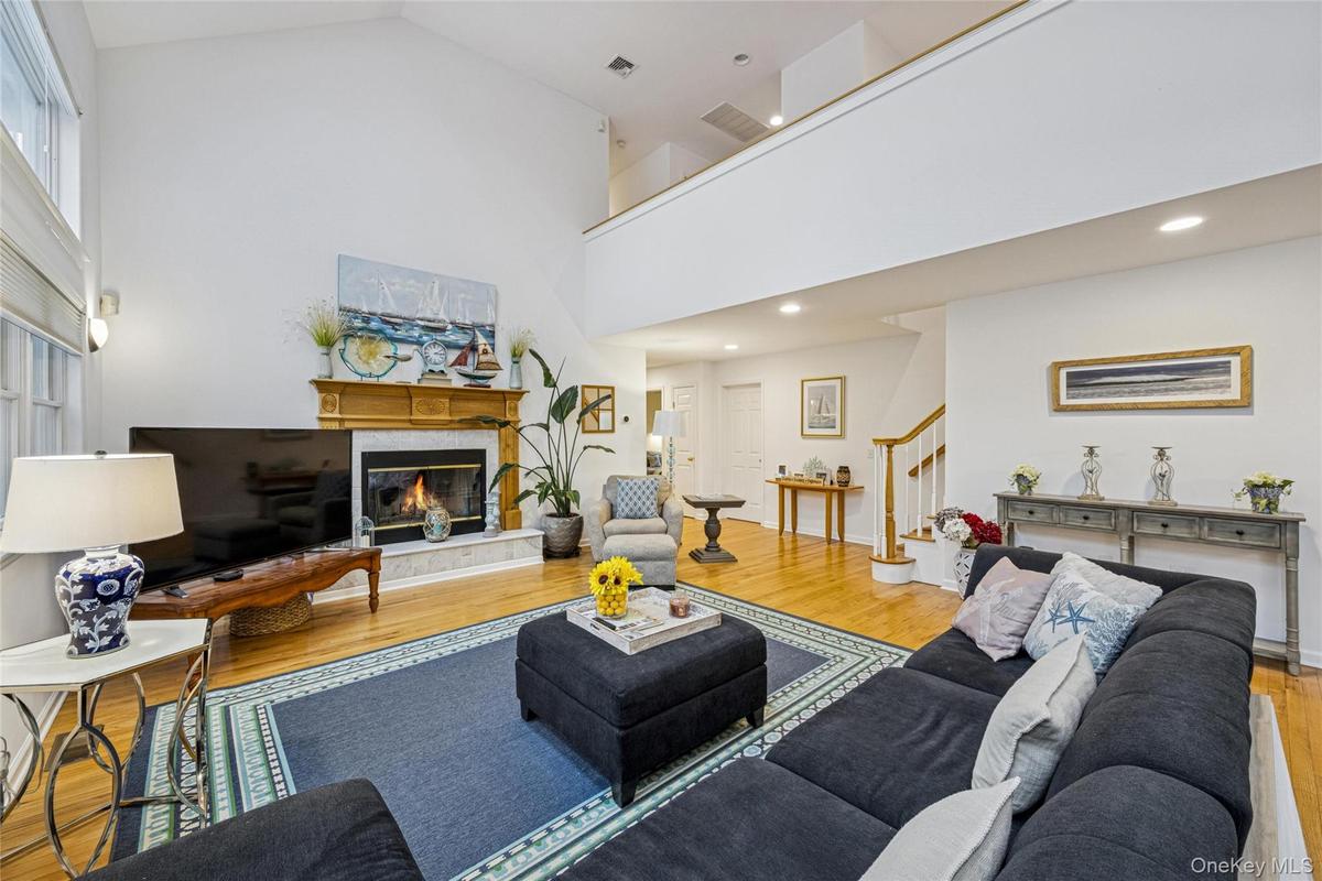 Living area featuring stairway, wood finished floors, a premium fireplace, and high vaulted ceiling