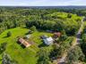 Expansive property featuring multiple structures, mature trees, open green spaces, and paved driveways