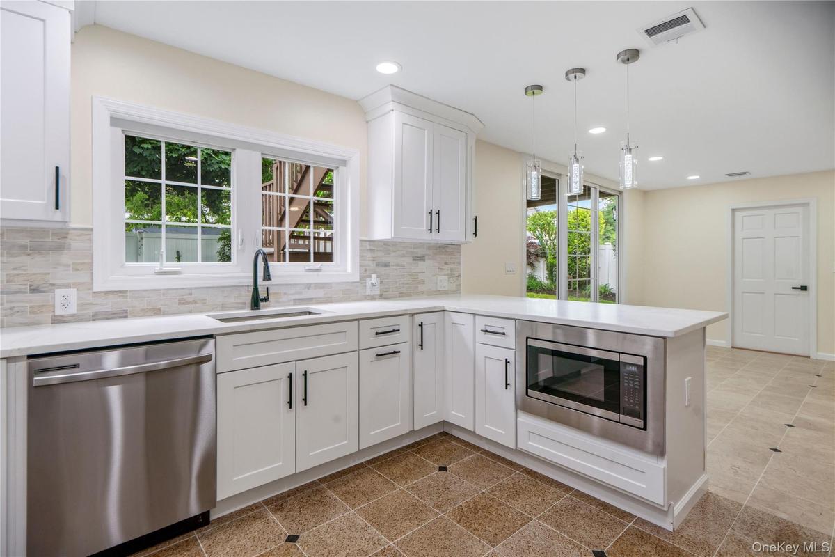 Modern kitchen featuring white cabinetry, stainless steel appliances, a white countertop, and a tiled backsplash
