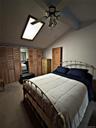 Bedroom featuring a vaulted ceiling with skylight, ceiling fan with light fixture, and wood louvered bifold closet doors