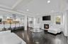 Living room with dark wood-style floors, a glass covered fireplace, recessed lighting, and crown molding